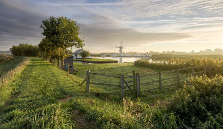A large windmill beside a waterway in The Broads National Park.