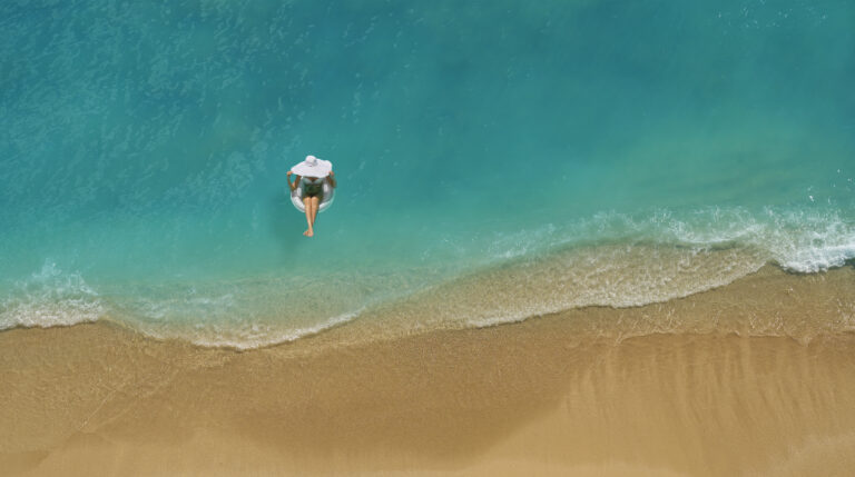 Woman floating in inner tube just steps from a tropical beach.