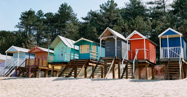 Colorful beach huts against the sand dunes.