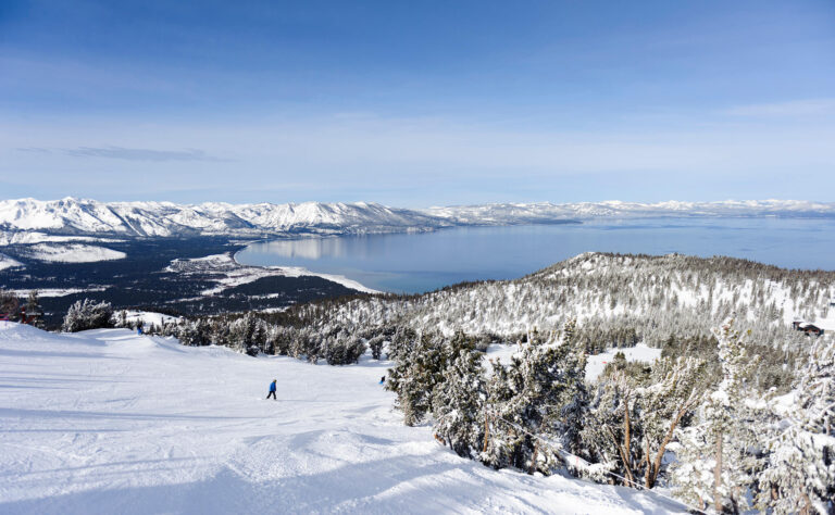 Snow skiers enjoy the slopes with a dramatic winter view of Lake Tahoe.