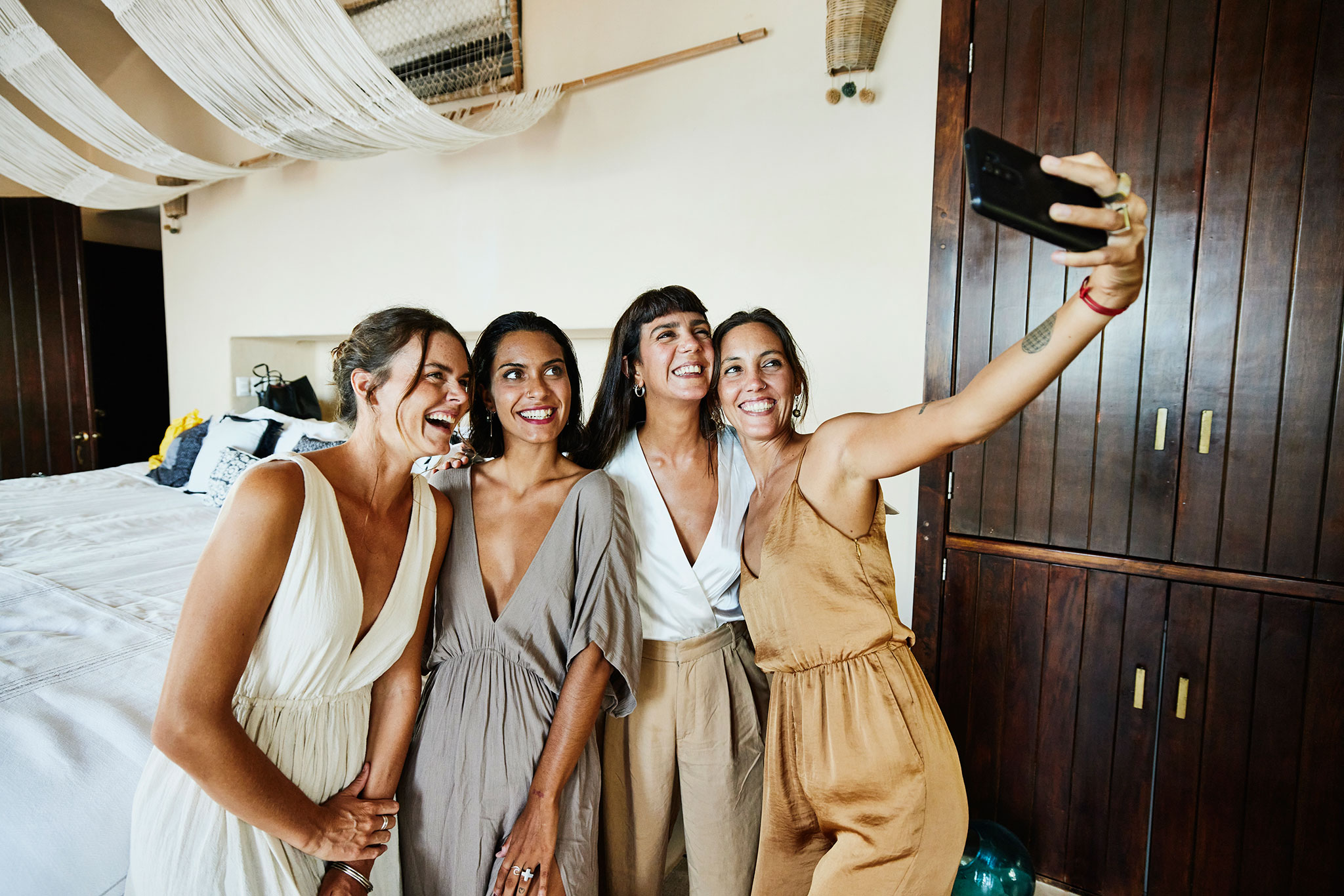 Four girlfriends pose for a selfie in a luxury hotel suite before a wedding.