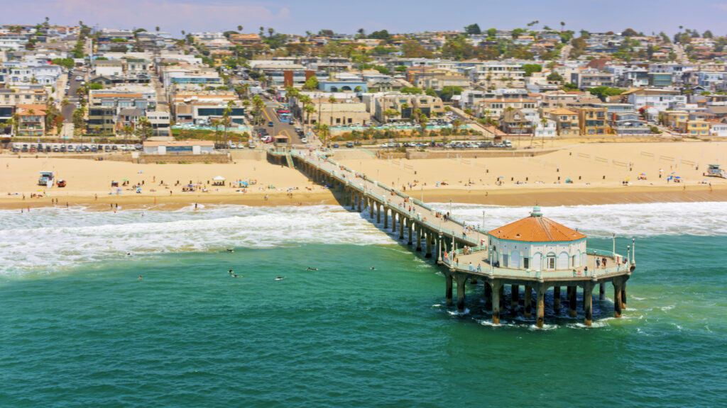 Aerial view of Huntington beach pier and wave splashing on beach against residential district, Orange County, Southern California, California, USA.