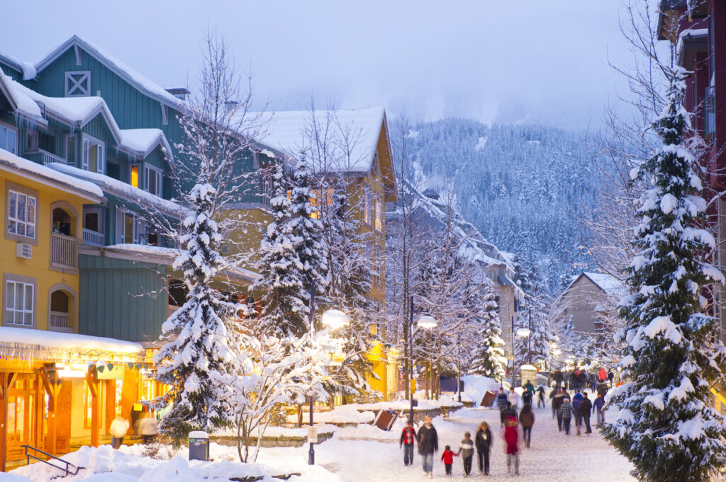 Whistler's world class pedestrian village filled with shops, hotels and restaurants blanketed with fresh snow at dusk