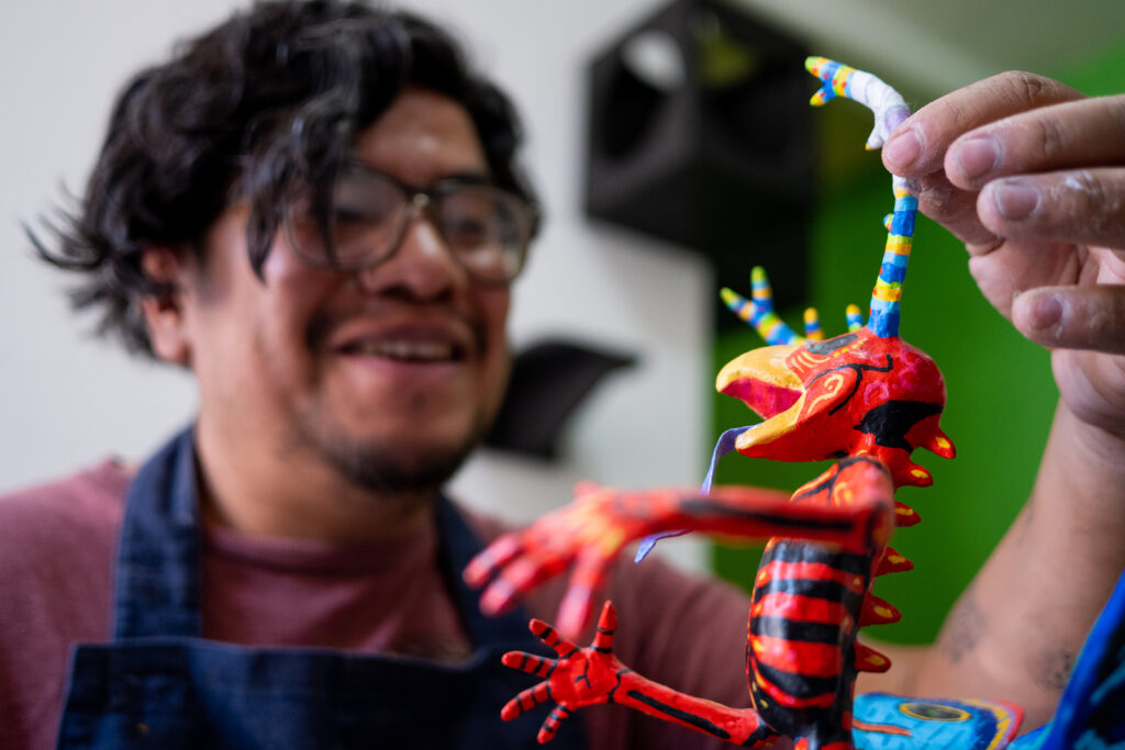 Mexican artisan painting an alebrije with a brush